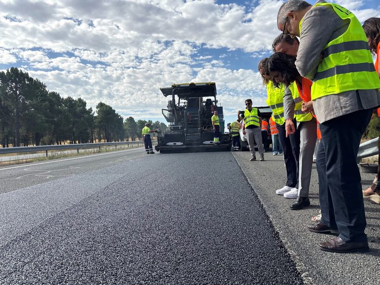 Vista del tramo experimental de la A-601 con el nuevo firme reciclado ya extendido y la maquinaria de asfaltado al fondo